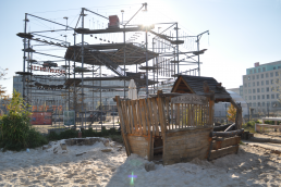 Wooden playground for kids with high rope course in the background